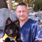 Headshot of Gary Uyeno sitting outside and holding a puppy.