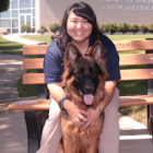 Headshot of Sydney Fujishige sitting on a bench with a German Sheperd dog.