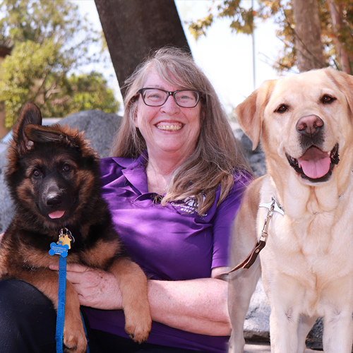 Headshot of Debbie Prince with two dogs sitting by their side.