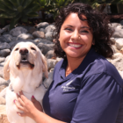 Headshot of Diane Rodriguez sitting outside with a Yellow Lab dog.