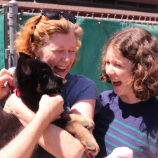 2 women, black lab puppy