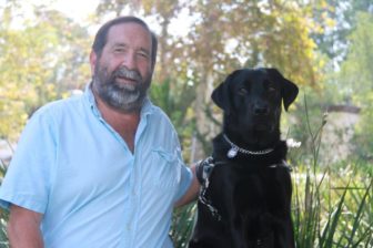 Dave Roultson sits next to his black Lab guide dog, Bernie