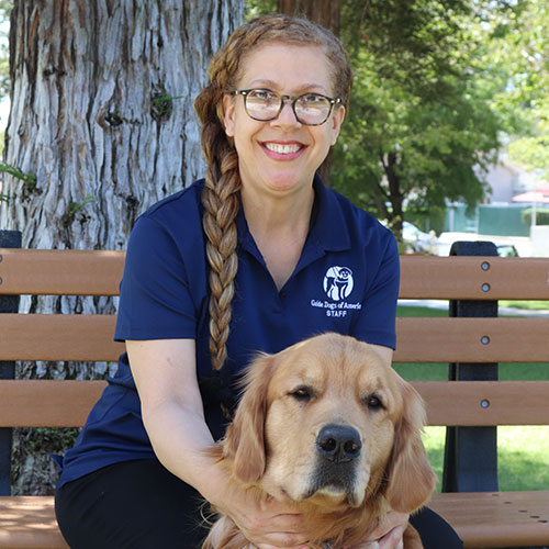 Headshot of Michelle Bell sitting outside with a Golden Retriever dog.