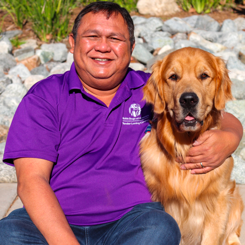 Headshot of Salvador Alob, Jr. sitting outside with a Golden Retriever dog.