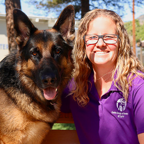 Headshot of Jamie Hunt sitting outside with a German Sheperd dog.