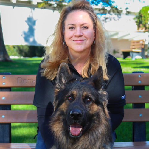 Headshot of Lisa Peterson sitting on a bench with a German Sheperd dog.