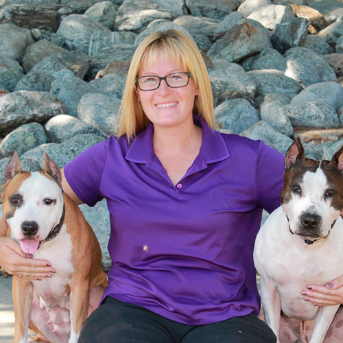 Headshot of Nicole Maples sitting outside with two Pitbull dogs.