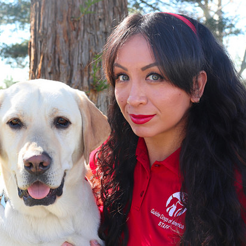 Headshot of Xochitl Sanchez sitting outside with a Yellow Lab dog.