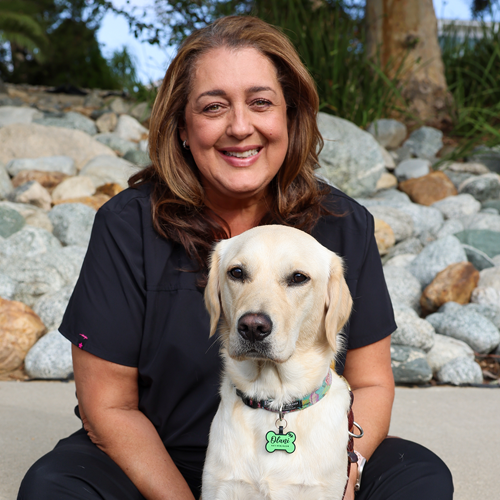 Headshot of Ceci Sanford sitting outside with a Yellow Lab dog.