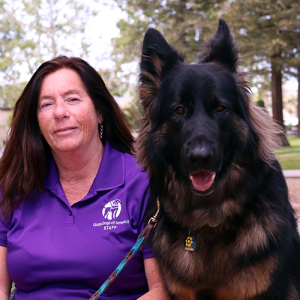 Headshot of Kris Wallace sitting next to a German Sheperd dog.