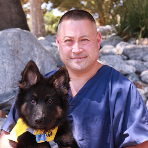 Headshot of Gary Uyeno sitting outside and holding a puppy.