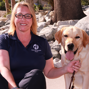 Headshot of Tara Doroginsky sitting outside with a Yellow Lab dog.